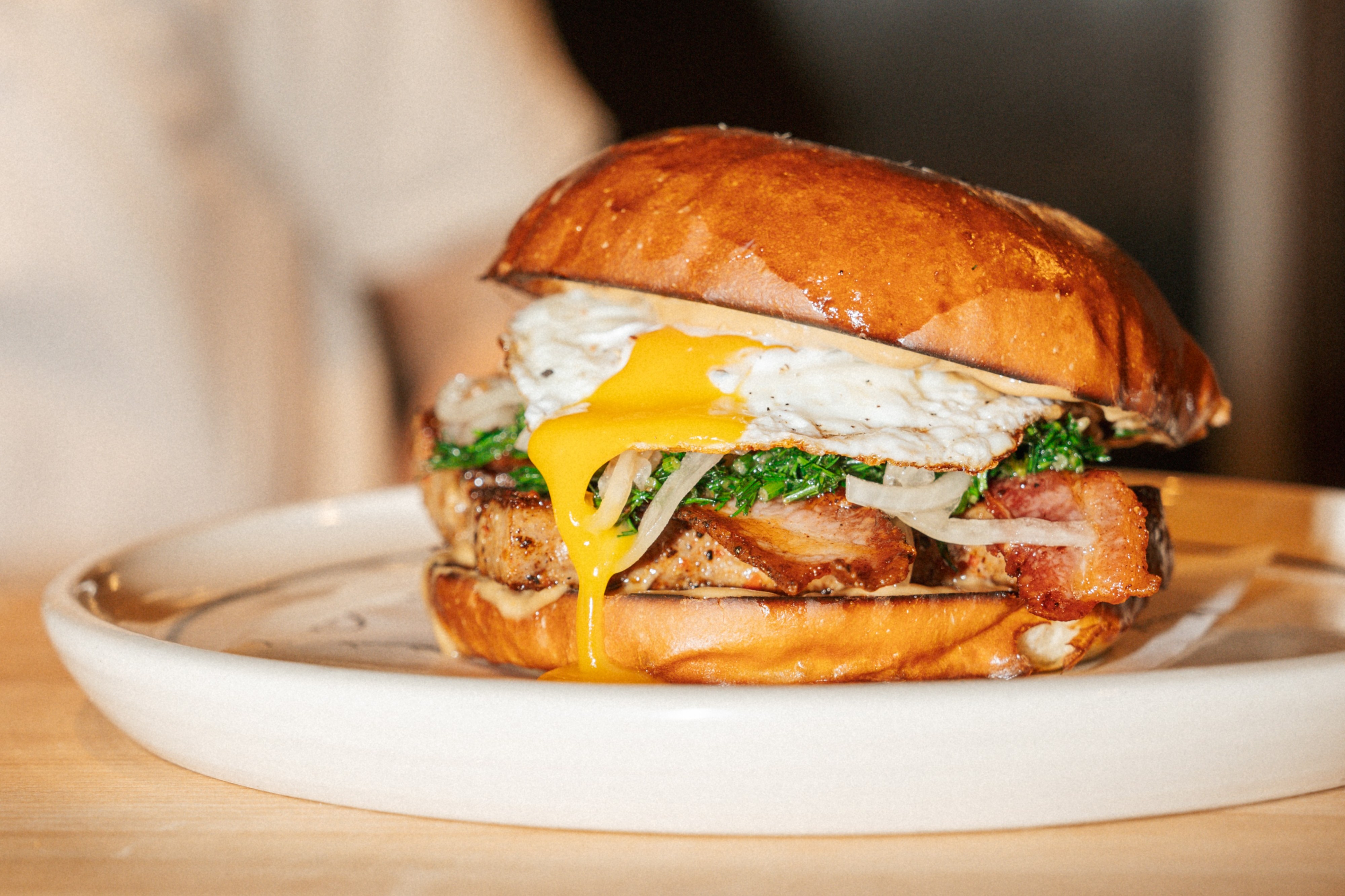 Glazed bun filled with a runny fried egg, bacon, pork, pickled onion and chopped herbs at Black Wheat Club, York